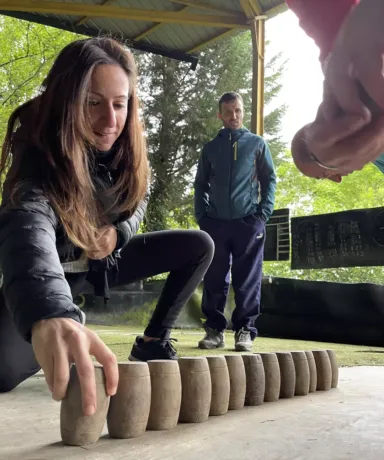 Mujer colocando bolos de madera en el suelo mientras un hombre mira