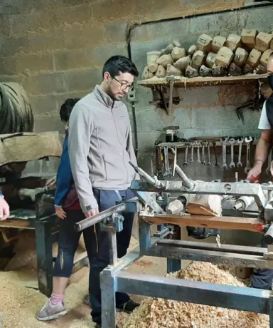 Grupo de personas observando como trabajan madera para realizar unas madreñas