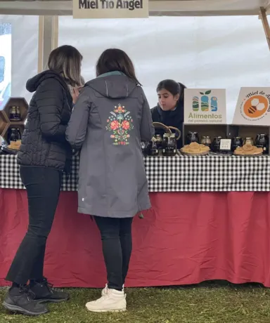 Dos mujeres mirando productos en un puesto de un mercado