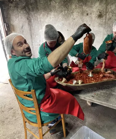 Grupo de personas sentadas embutiendo morcillas