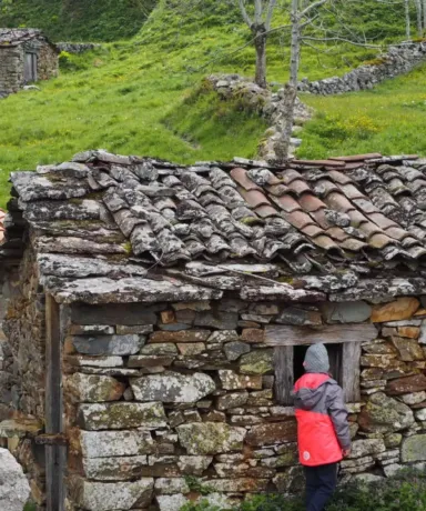 Dos personas frente a una cabaña de piedra en el monte