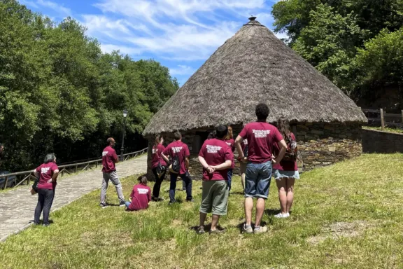 Varias personas junto a una palloza