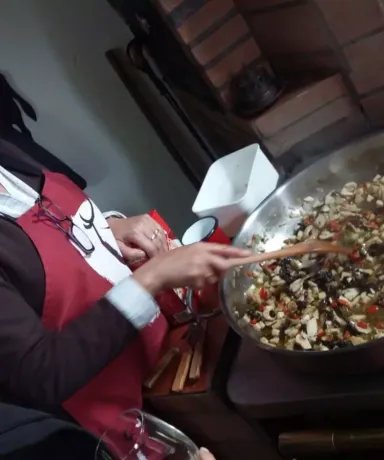 Mujer removiendo con una cuchara de madera los ingredientes en una olla grande mientras otra observa